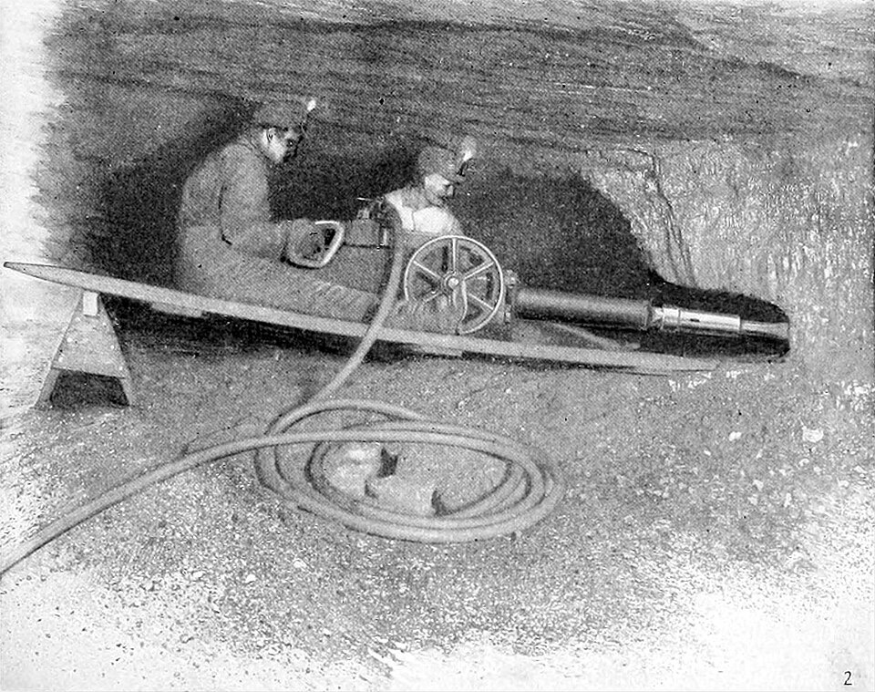 Two miners underground with an early mechanical coal cutter, 1905